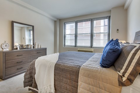 A bedroom with a bed, a dresser, and a window.